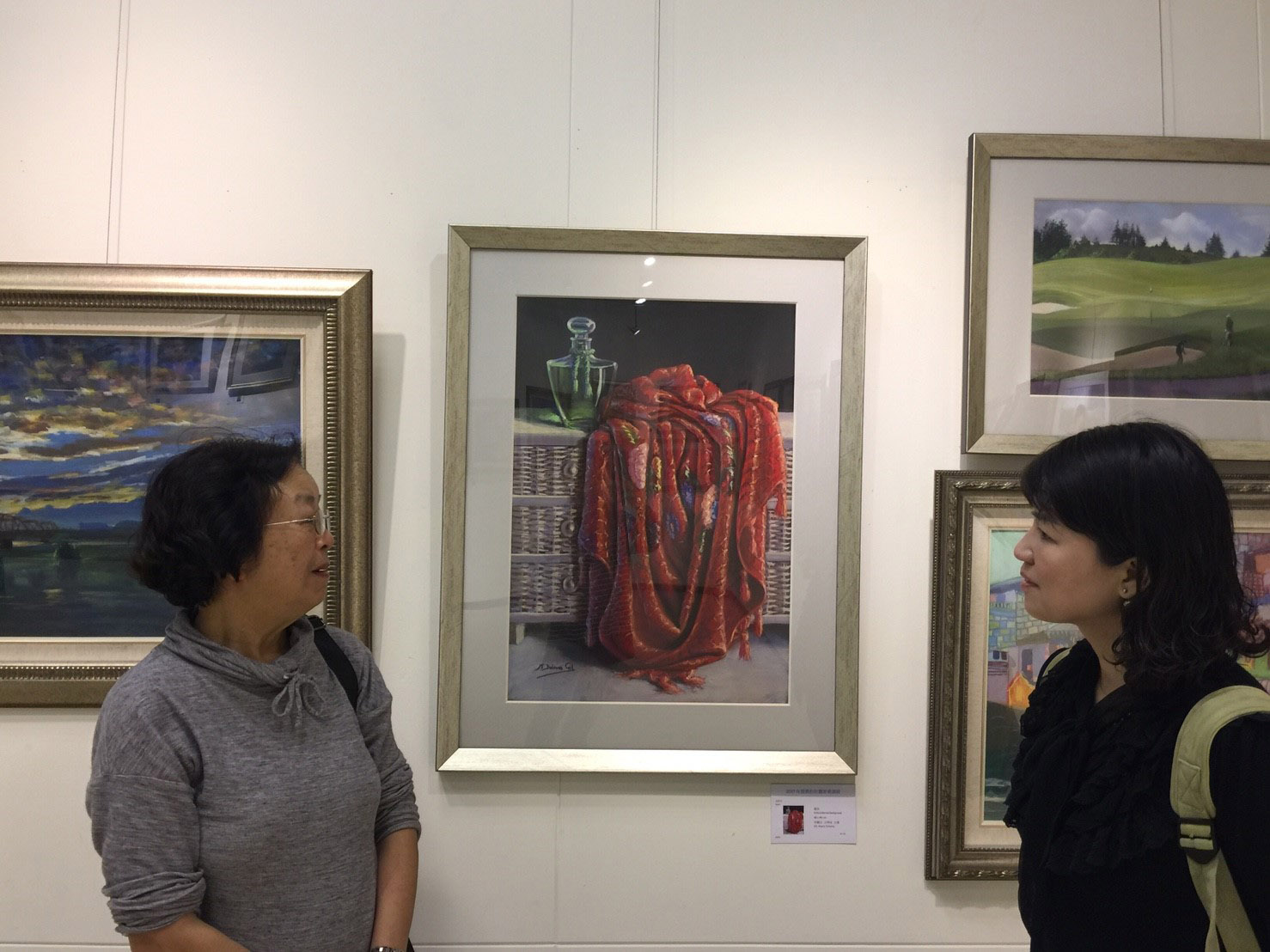 Nancy Yang con una visitante junto al cuadro de MD Gil